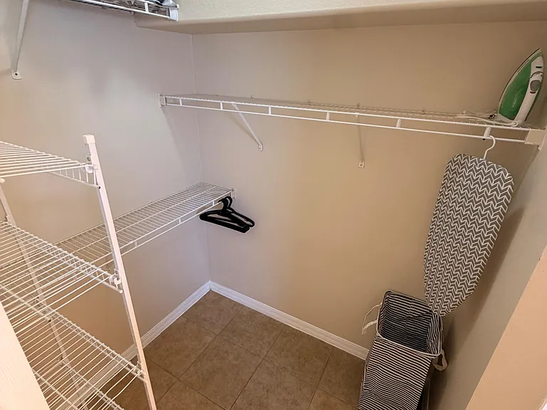 Spacious walk-in storage closet with multiple wire shelves and hanging space, plus durable tile flooring for easy upkeep.