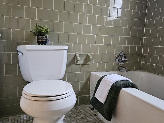 Recently reglazed tub with trendy green ceramic tile.