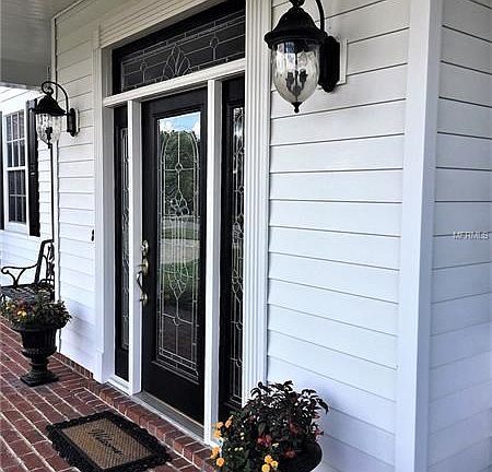 Beautiful leaded glass doors are flanked by classic lanterns & planters
