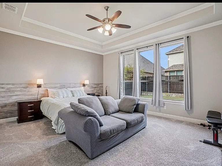 Large Primary bedroom with accent wall, tray ceiling, fan