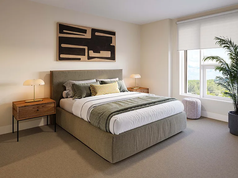 Elegant bedroom with a plush bed, stylish bedside tables, modern art, and large windows overlooking greenery.