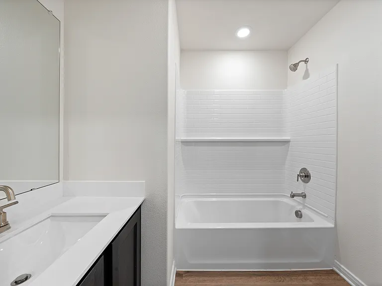 The secondary bathroom has a large vanity space and a shower-tub combo.