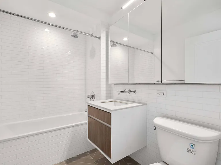 Bathroom with floating sink, large mirrors, and tub