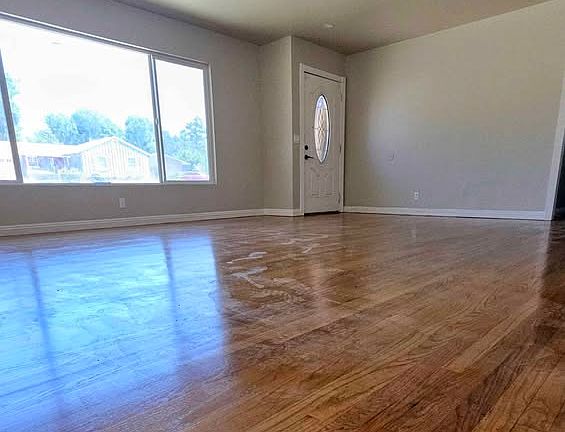 Spacious living area with refinished hardwood floors, recessed lighting, and a large front window.