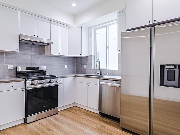 Kitchen with brand new stainless steel Samsung appliances: fridge, gas stove, and dishwasher.
