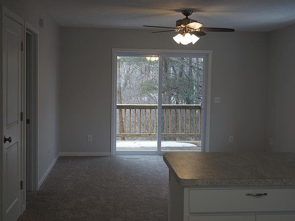 Open concept living room/kitchen area has 6 ft. sliding door which opens onto a spacious deck overlooking a peaceful wooded area.
