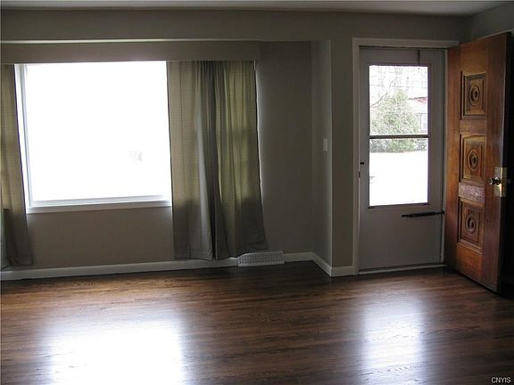 Freshly Painted living room and Gorgeous Refinished Mahogany Color Oak Hardwood floors. Stunning attention to detail on the solid Oak Front Door. This is the view from the kitchen into the Living area, so bright and sunny!