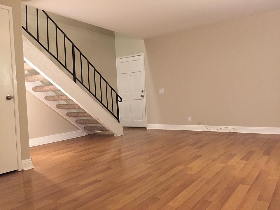 Downstairs entry way and living room with storage closet behind the stairs.