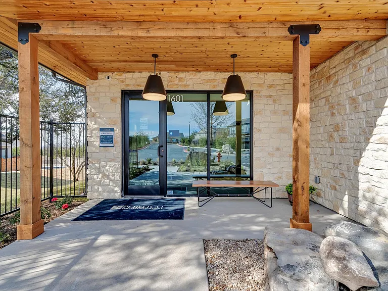 A modern house entrance with a stone wall and a glass door.