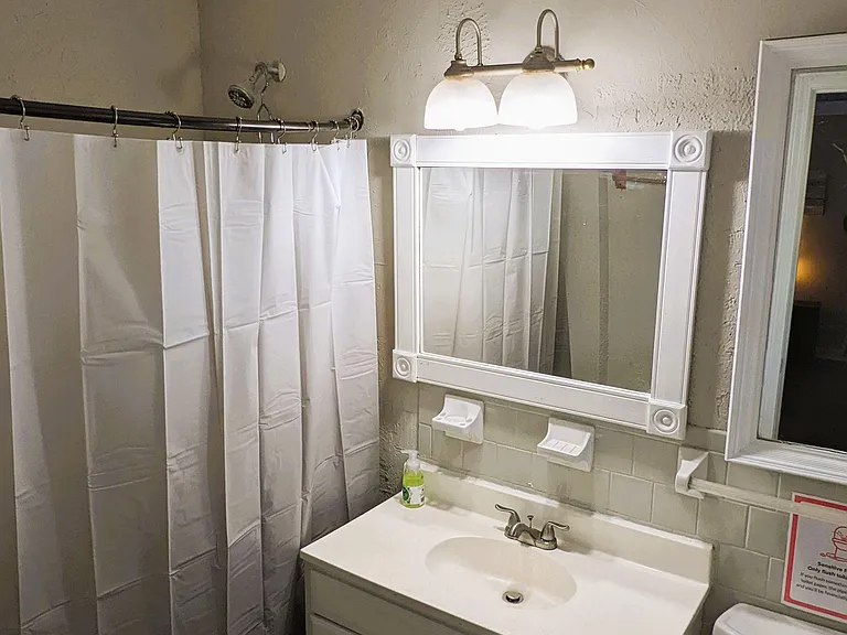 Full bathroom with a tub/shower combo, vanity sink with storage, and a large framed mirror with overhead lighting.
