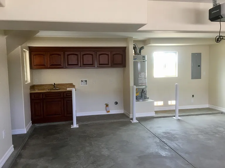 GARAGE INTERIOR SHOWING ELECTRIC CAR OUTLET UNDER THE FUSE BOX ON THE RIGHT! THE LAUNDRY NOOK HAS DIRECT ACCESS INTO THE LIVING ROOM FOR YOUR CONVIENCE. THE LAUNDRY NOOK PICTURED IN THIS PHOTO HAS A SLIGHTLY DIFFERENT GRANITE COUNTERTOP THAN IN THE ACTUA