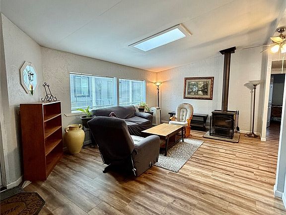 Spacious living room area with skylight and wood burning stove.>