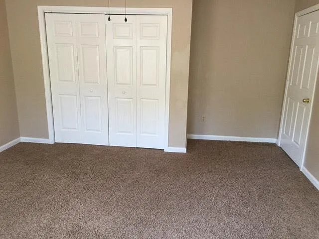 This is another picture of the front bedroom, showing the closet doors closed and the bedroom door closed opposite the windows.
