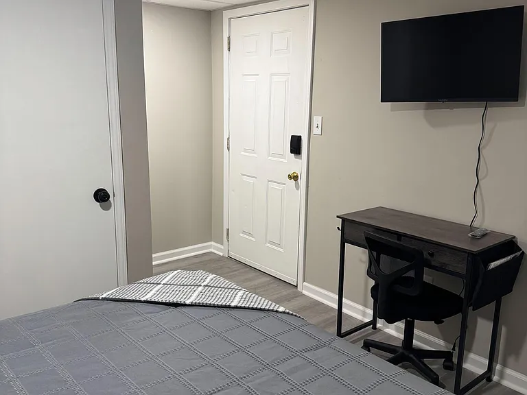 Private bedroom with LVP flooring, a dedicated work desk, and wall-mounted TV for comfortable everyday living.