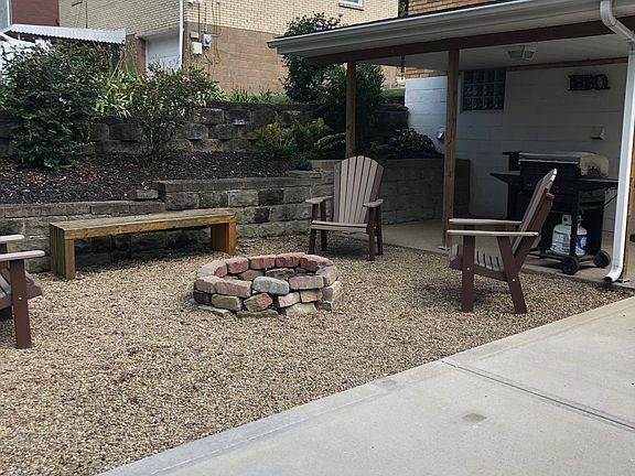 Covered back porch that leads to the walk out basement. Electrical outlet and lighting available under the porch. The fire pit and grill are among the amenities included with the property.