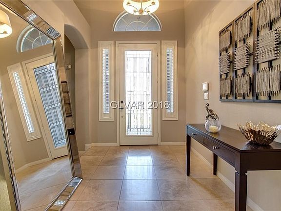 Enter through beveled glass door into hallway with travertine tile and two-tone paint.