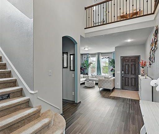 Entryway with stairway, dark wood-style floors, arched walkways, a towering ceiling, and recessed lighting