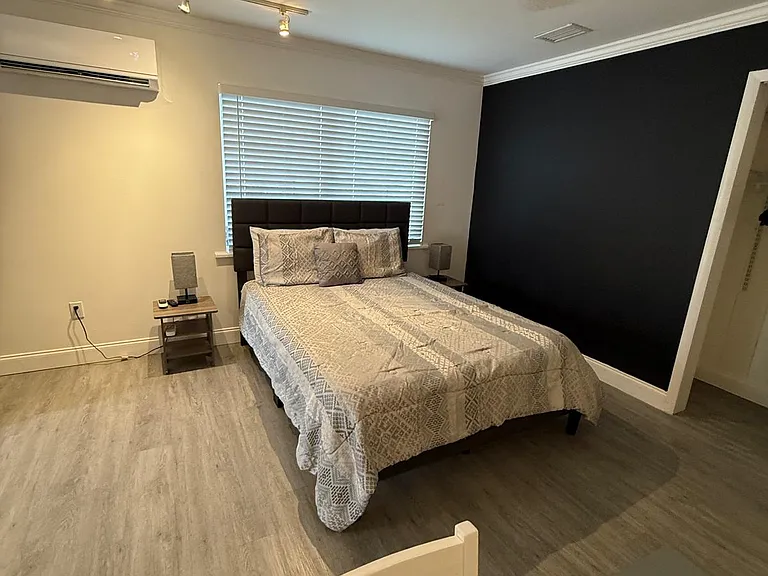 Stylish studio featuring a queen bed, nightstands, lamps, and premium linens.