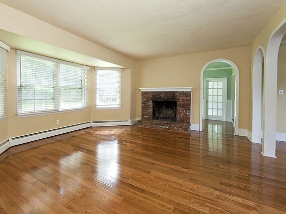 Living room with fireplace and newly refinished, gleaming hardwood floors.