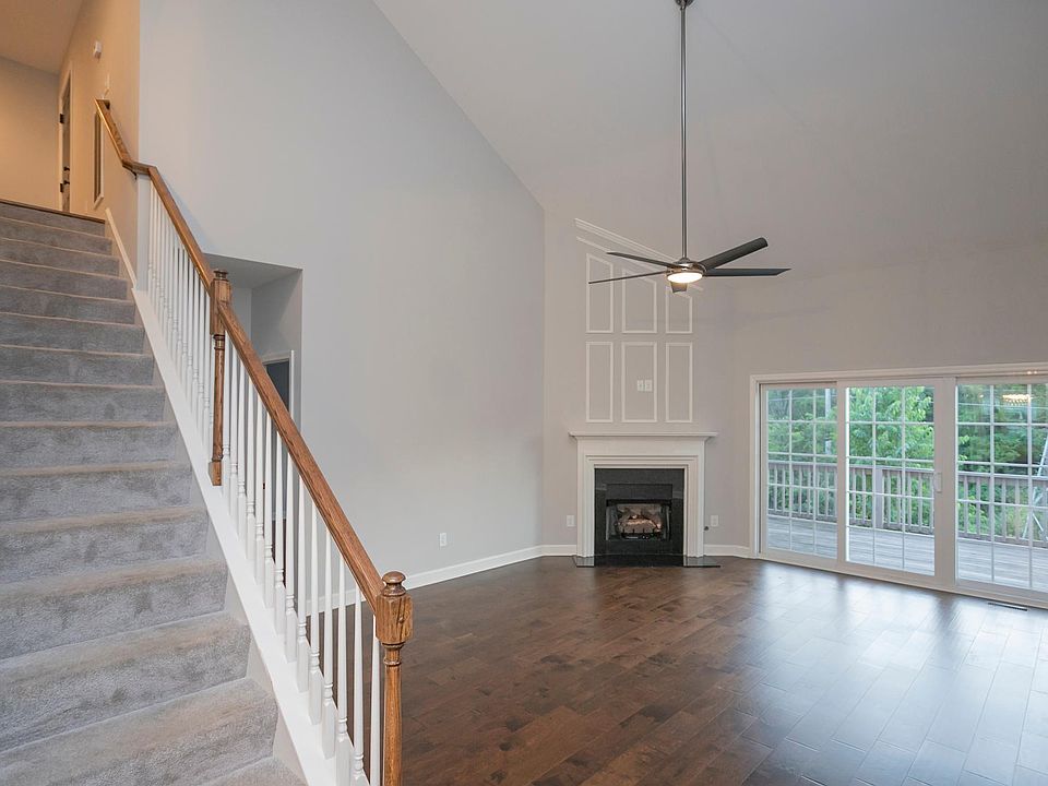 large living room, with fireplace, hardwood floors, sliding door to the deck and high vaulted ceilings