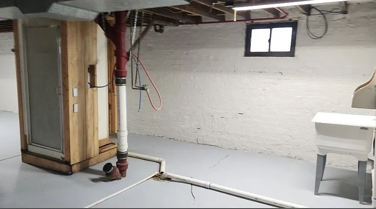 Another view of the basement showing the free-standing shower, sink and laundry hookups.