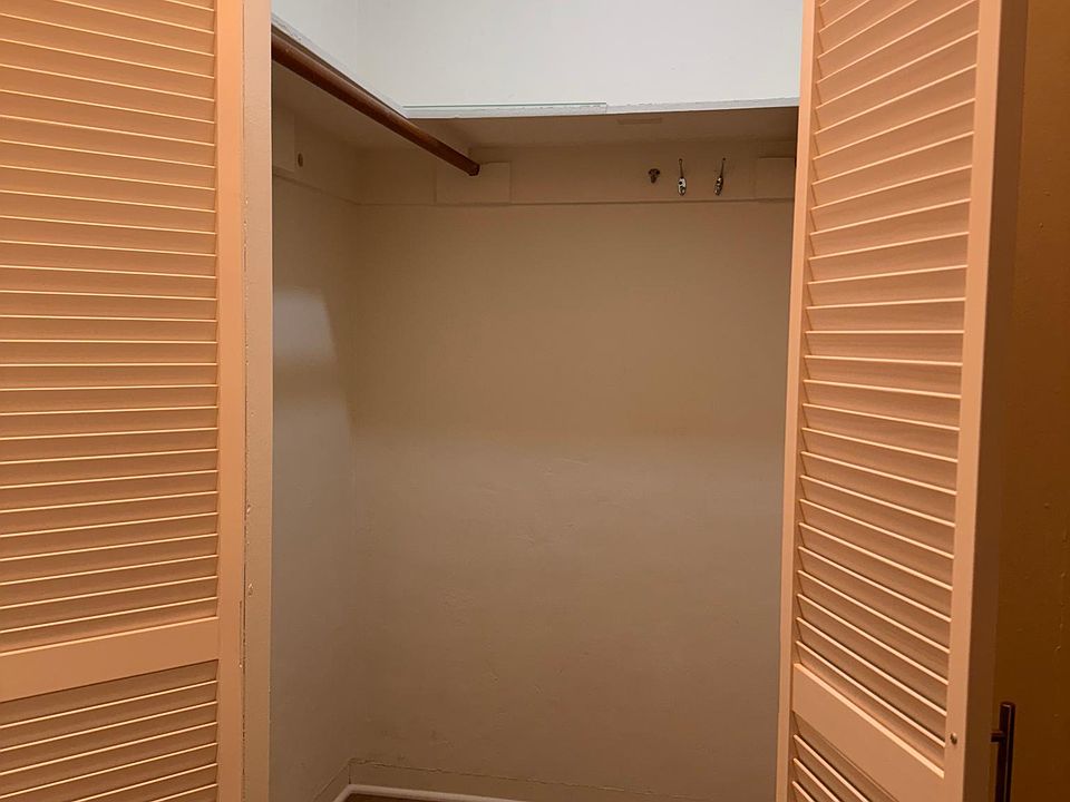 Walk-in closet has poles to the right and left with louvered door for air circulation this near the ocean.