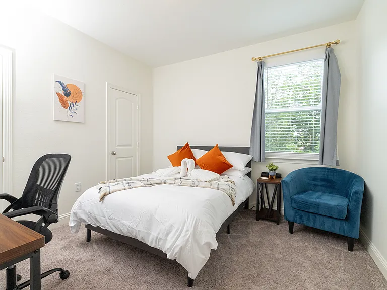 Bedroom 3 features a queen bed, cozy corner chair, plus a desk and chair_ideal for remote work or relaxing in style.