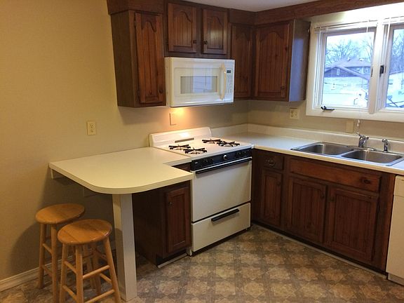 View of kitchen showing breakfast bar with stools, nice windows over the sink for great natural light and ventilation. New built-in microwave above the stove.