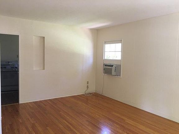 Other half of the living room. Powerful wall AC and entrance to the kitchen (left)