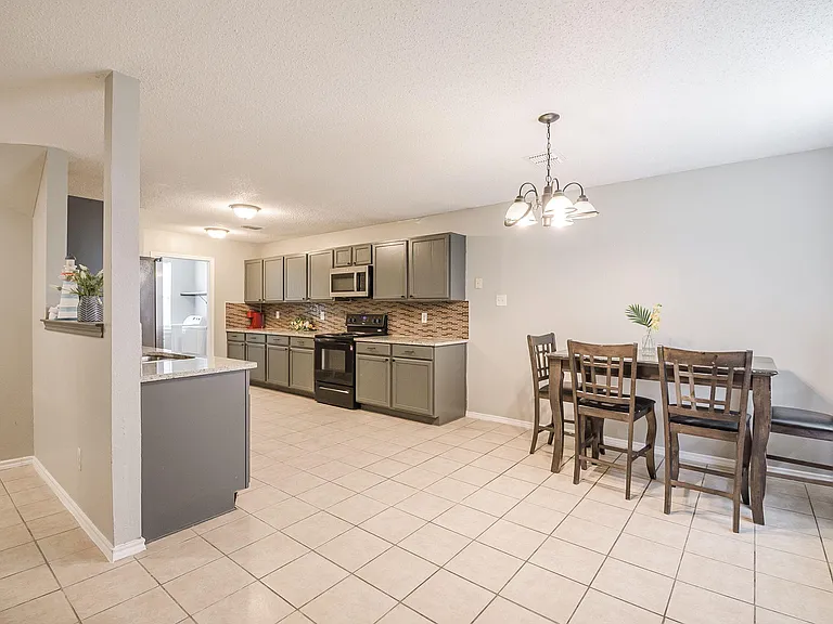 Open kitchen with ample cabinetry, tile floors, and a dedicated dining nook, plus convenient passthrough counter seating.