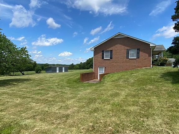 Side of house with basement entrance and view of biggest storage shed.