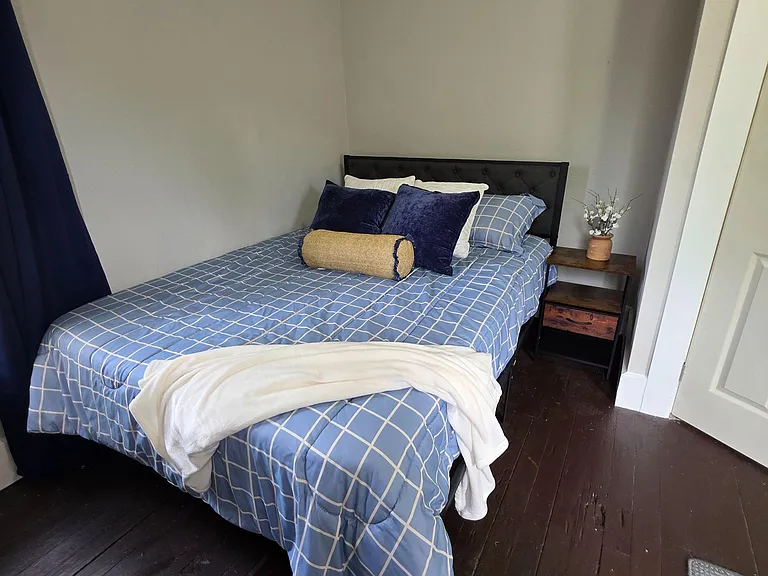 Furnished bedroom with a full bed, nightstand, and dark wood floorsan easy, move-in-ready space for restful nights.