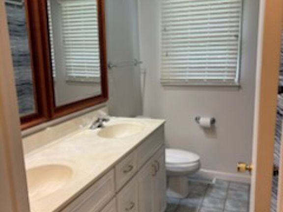 main bathroom, double sink with cherry wood framed mirrors, full bathtub with shower, tiled floor, privacy glass on lower window.