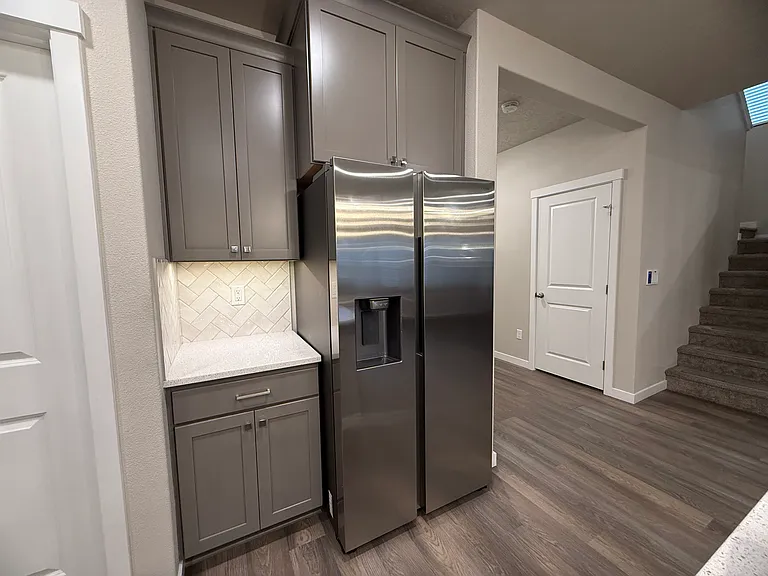 Refrigerator area with additional cabinetry looking toward the stairs and main living areas.
