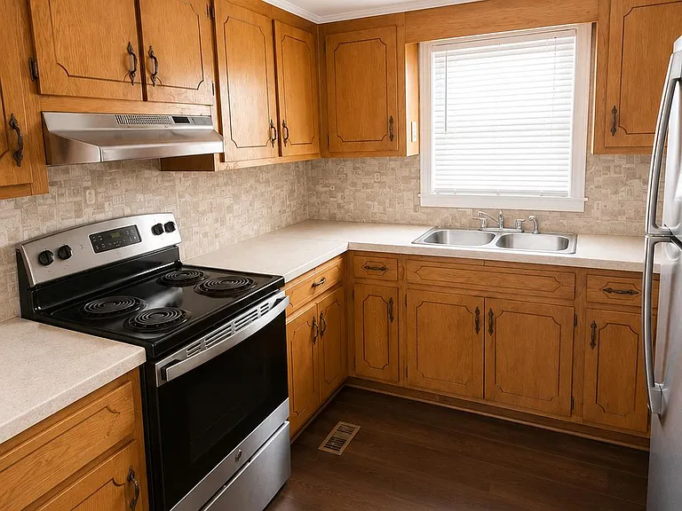 Efficient U-shaped kitchen with ample wood cabinetry, laminate counters, double-basin sink, and stainless appliances.