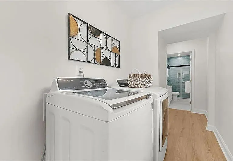 Dedicated laundry area with full-size washer and dryer, set off a hallway with easy access to the adjacent bathroom.