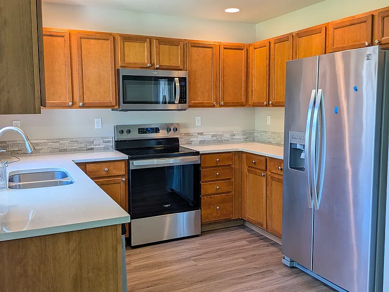 Kitchen with quartz counter tops has all SS appliances, including NEW glass top stove, refrig w ice maker and garb disposal