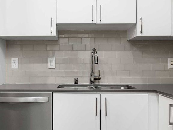 Renovated Package I kitchen with quartz countertops, white cabinetry, stainless steel appliances, hard surface vinyl plank flooring, and tile backsplash