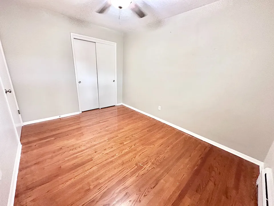 Bright, airy room with elegant hardwood floors and a ceiling fan, perfect for a cozy bedroom or home office.
