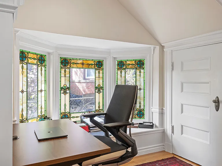 Second office nook on first floor under grand staircase to second floor. Features period details including stain glass windows and molding.