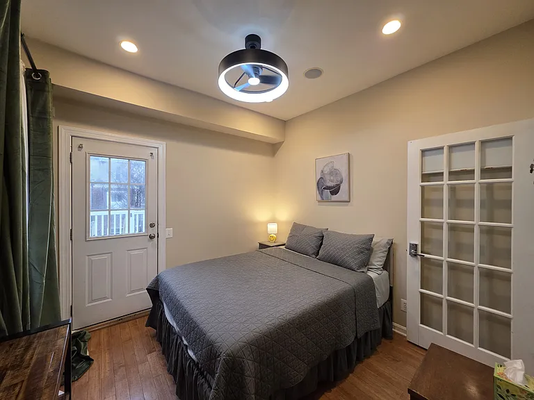 main floor bedroom with new 55" smart TV and LED ceiling fan; medium firm topper mattress