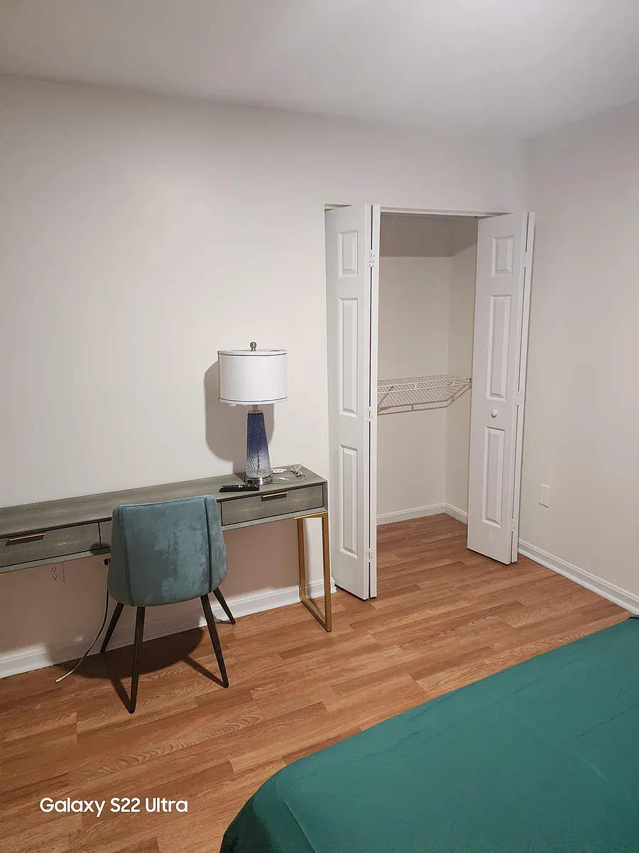 Bedroom area with hardwood floors, a work desk setup, and an open closet with shelving for convenient storage. - Crandall Rd
