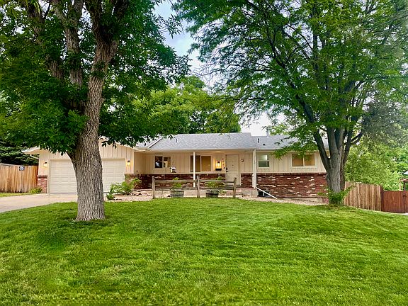Front of house- spacious front yard with mature trees, large driveway and two car garage