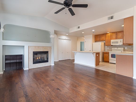 Open living area and kitchen with ga fireplace and ceiling fan