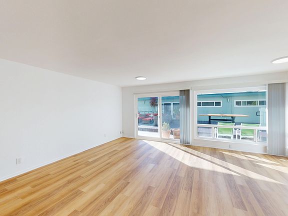 Room with wood floor, large window, sliding door to deck with outdoor furniture