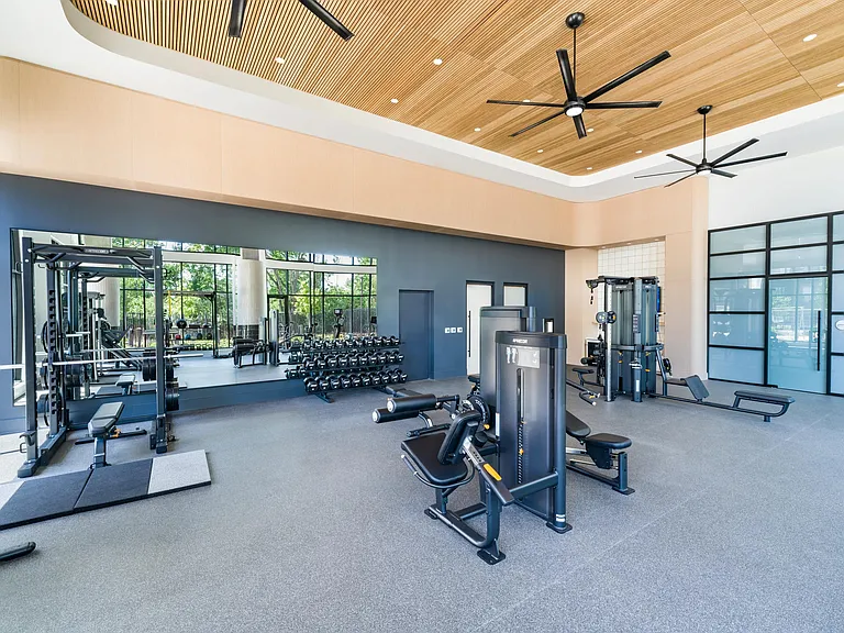 Spacious fitness studio with mirrored walls, strength equipment, and open training zones designed for balanced workouts and everyday performance.