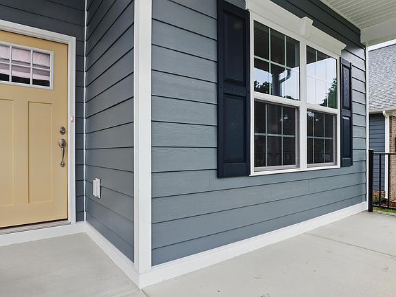 Front porch of a Somerset Hill house with blue siding, beige door, black shutters, and large windows
