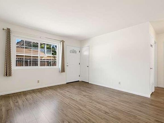 Living room view showing front door and guest closet, and small hallway