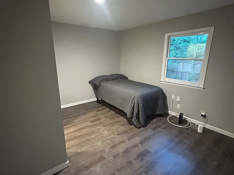 Private bedroom with wood-look flooring, a window for natural light, and ample wall space for storage and a desk.