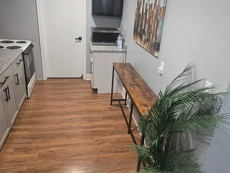 Efficient kitchen nook with granite-look counters, upper cabinetry, microwave space, and durable wood-style flooring.